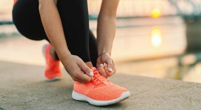 person lacing up orange shoes to go walking