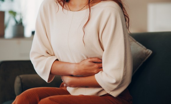 woman holding belly due to symptoms of IBD or IBS