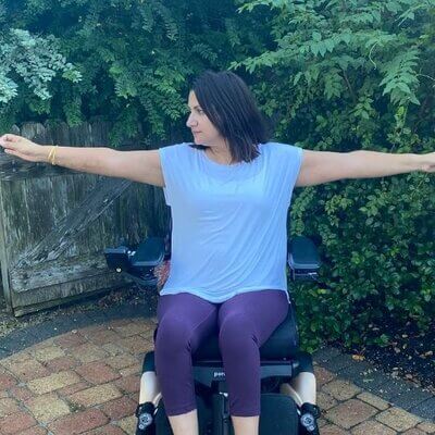 Meena demonstrating a balancing yoga pose in her wheelchair